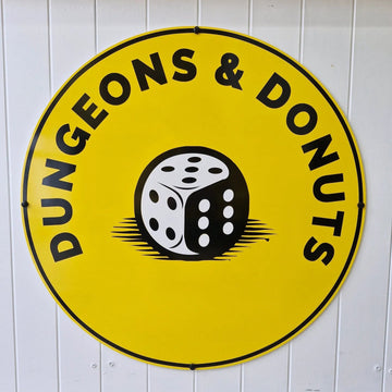 Circular sign with 'Dungeons & Donuts' and a dice graphic on a white wall.